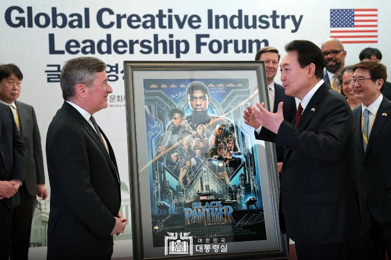 President Yoon Suk Yeol (right) on April 27 talks with Charles Rivkin, chairman and CEO of the Motion Picture Association (MPA), at the Global Creative Industry Leadership Forum held at MPA headquarters in Washington. "There are no national borders between countries in the culture industry," the president said. "We will get rid of anything that does not meet global standards."   President Yoon received from Rivkin a poster of the movie "Black Panther" signed by the latter's director Ryan Coogler, and said, "Because key scenes in 'Black Panther' were filmed in Busan, I will actively provide support for joint production of content by both countries."