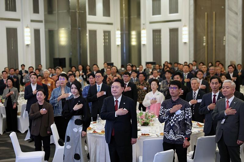 President Yoon Suk Yeol (third from left in front row) and first lady Kim Keon Hee (second from left in front row) on Sept. 5 stand in salute while listening to the Korean national anthem at a dinner for Korean expats in Indonesia at a hotel in Jakarta. (Jeon Han)